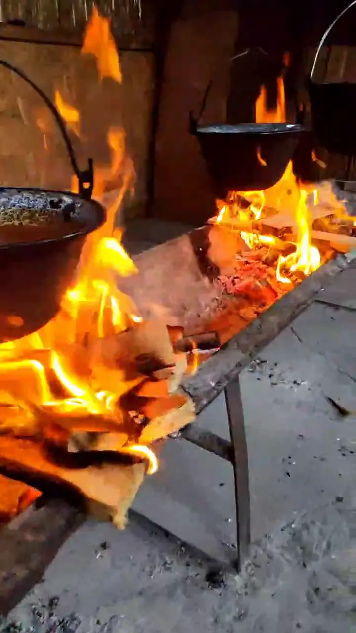 Snimak kotlića riblje čorbe nad visokim plamenom ognjišta